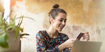 Woman excitedly looking at phone and laptop