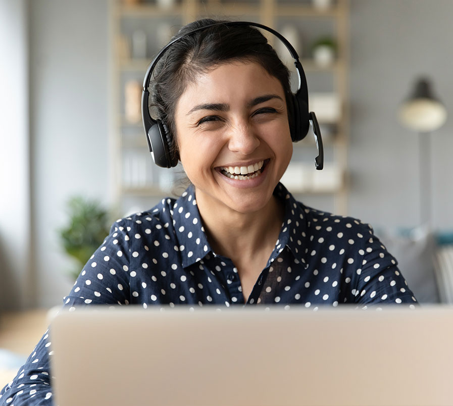 person with headphones smiling at desktop