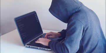 website hacker with hoodie, testing security of WordPress website on laptop